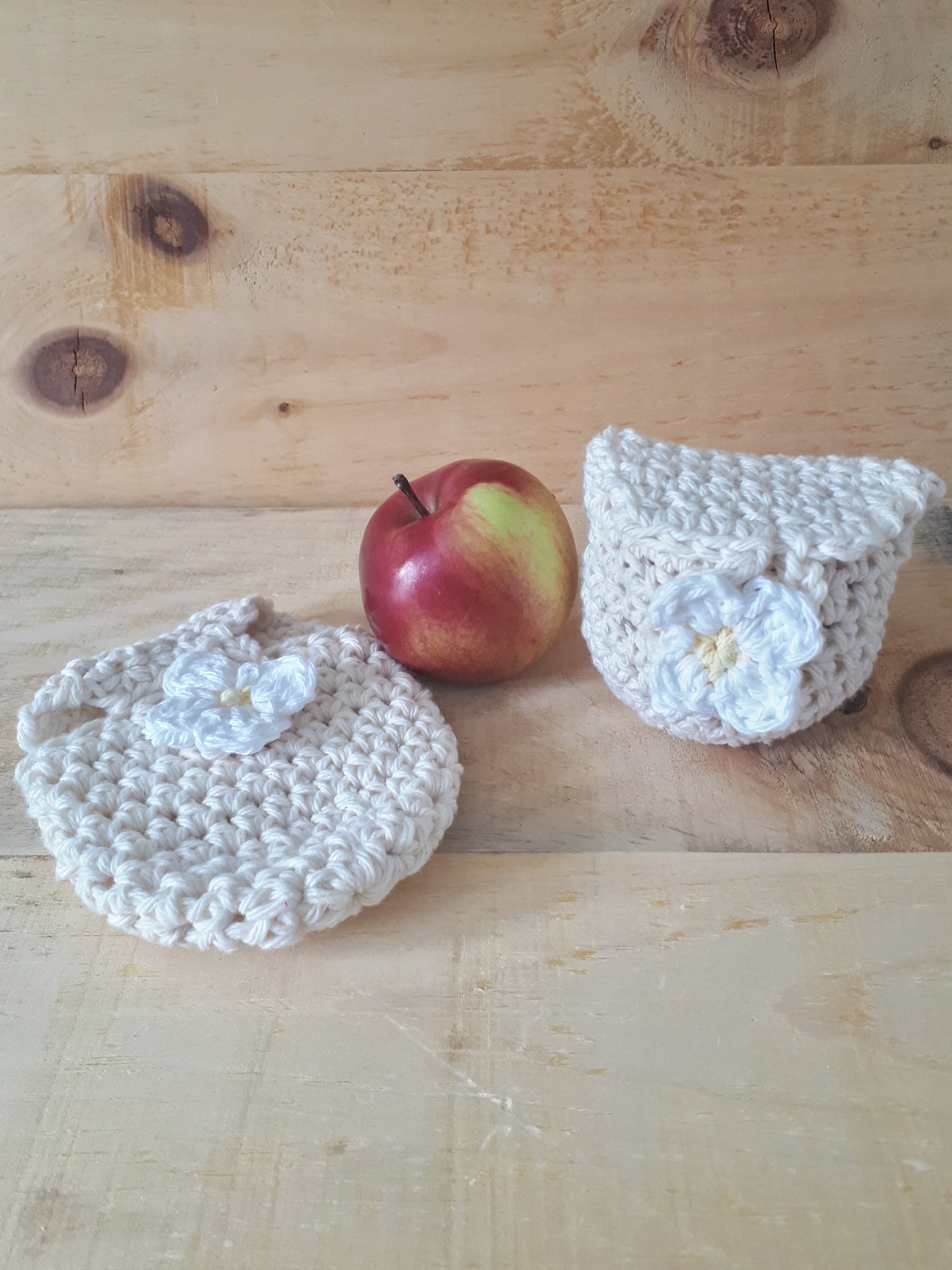 Crochet pouch with flower sits on barn wood beside apple