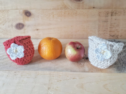 Red and natural cotton crochet pouch sits on barn wood beside apple and orange. 5 petal flower applique button.